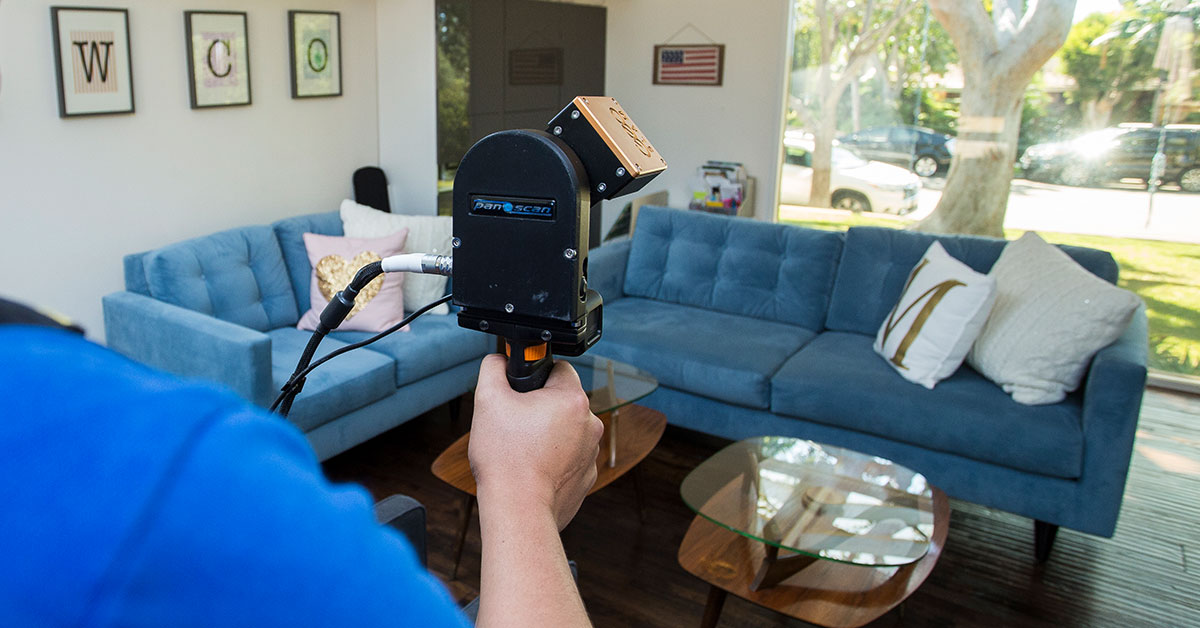 Image of 3D laser scanner capturing point cloud data in a residential living room during an As-Built survey site visit.